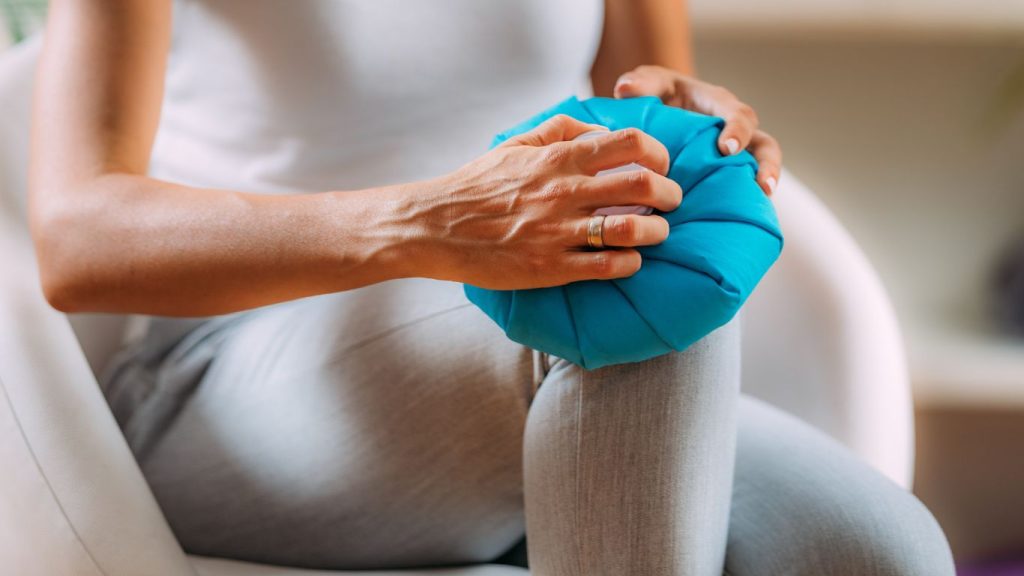 woman holds ice pack on knee