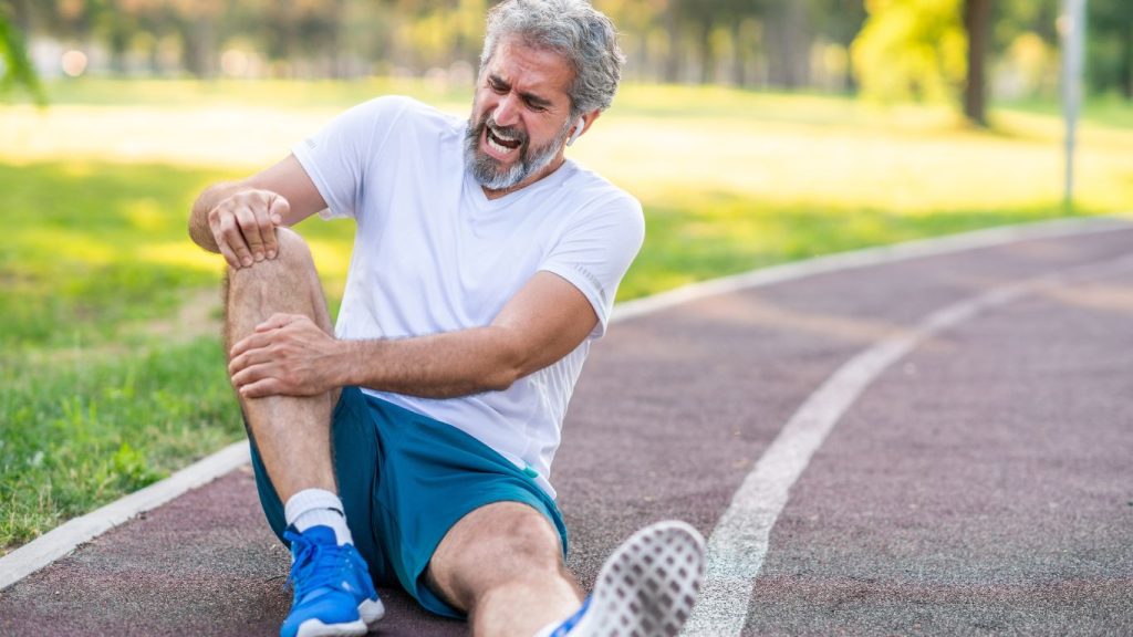 runners knee man on road while jogging with sore knee
