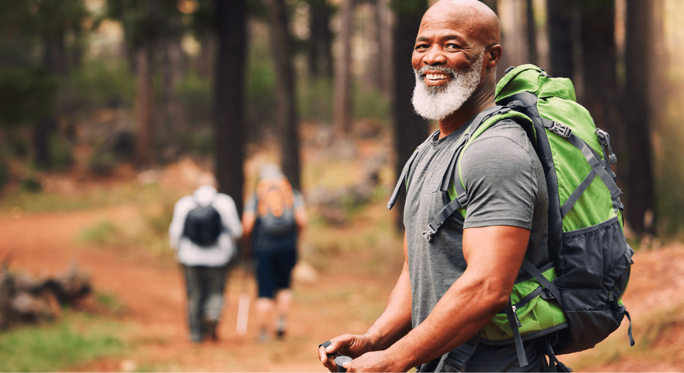 Man with hiking pack smiling, hiking through forest