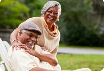 Older couple, smiling on bench in a park
