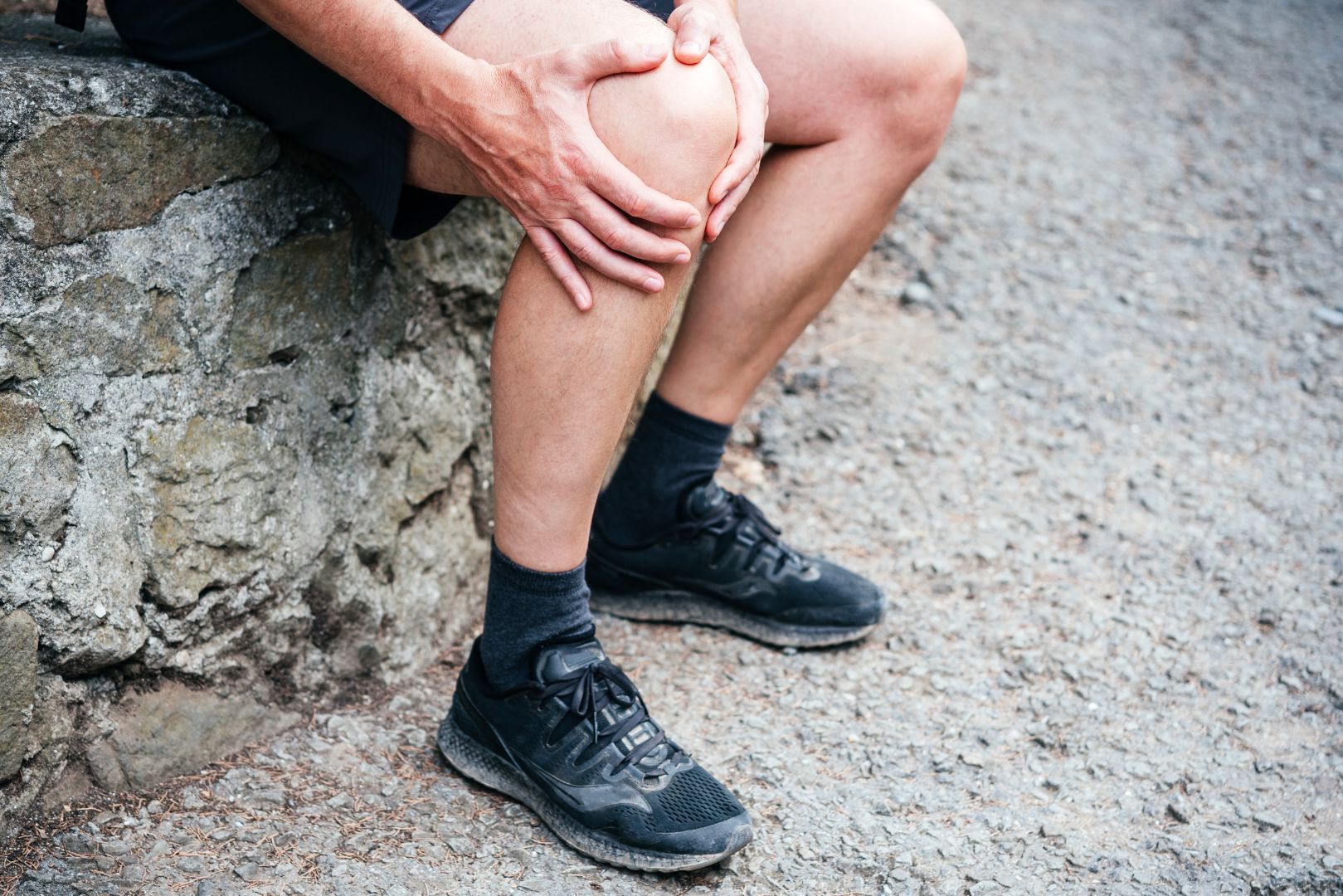 An older man holds his knee from pain from IT Band Syndrome.