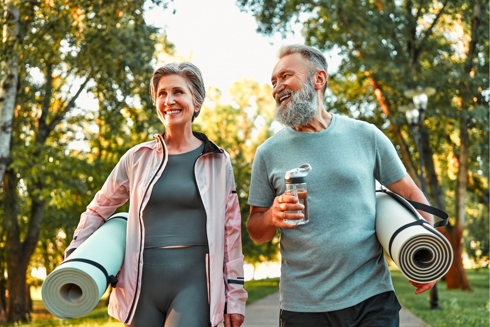 An older woman and man carry yoga mats for exercise after a PRP injection.