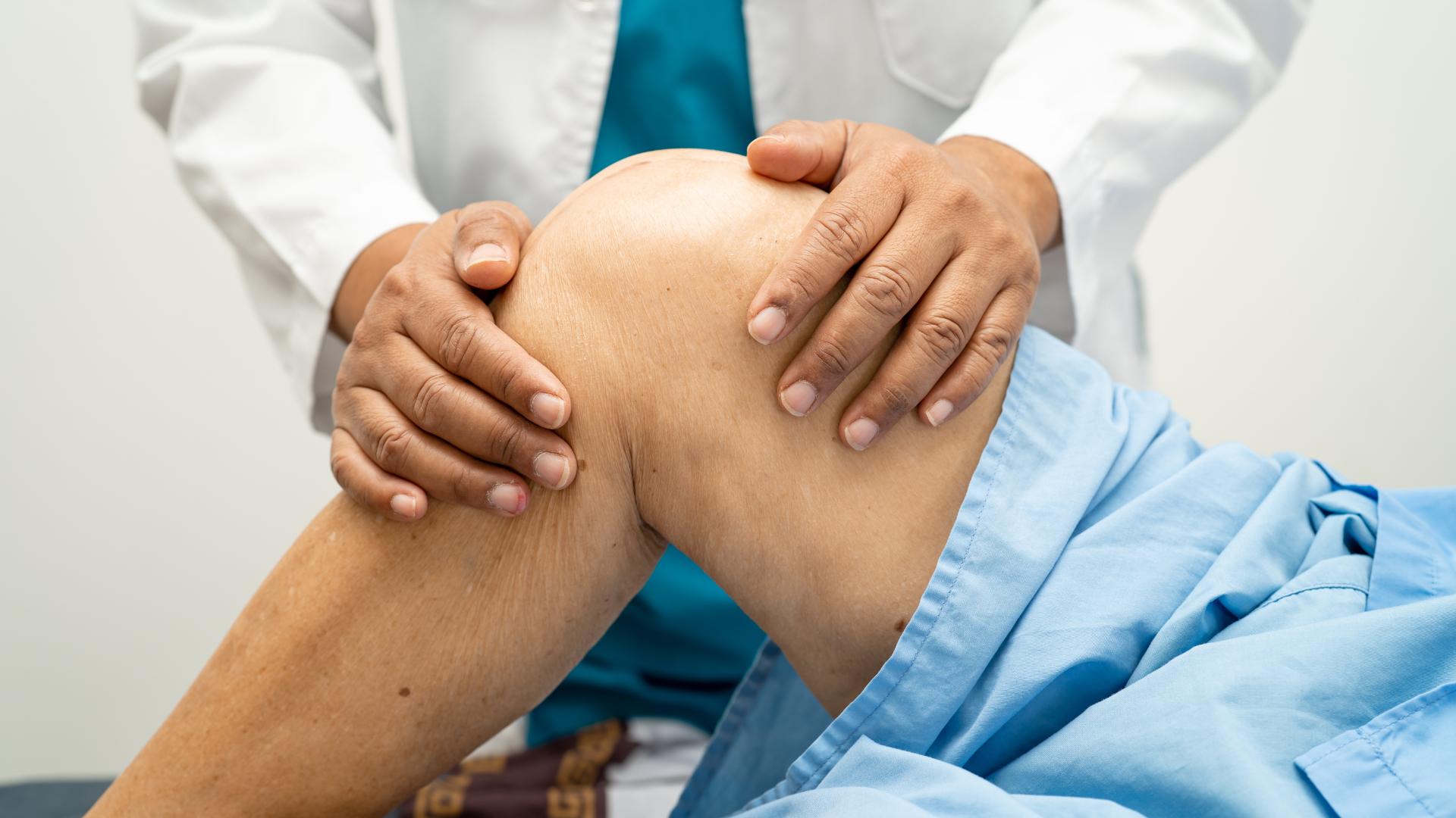 Doctor examines older patient's knee.