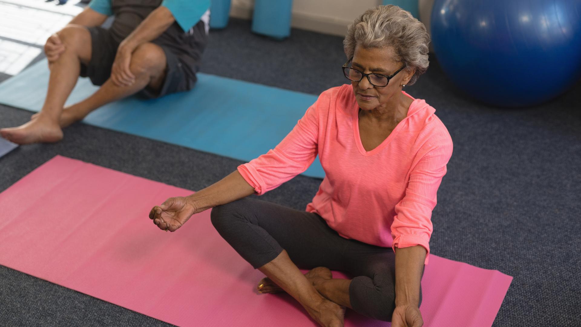 elderly woman doing yoga seated in tailors position with crossed legs.