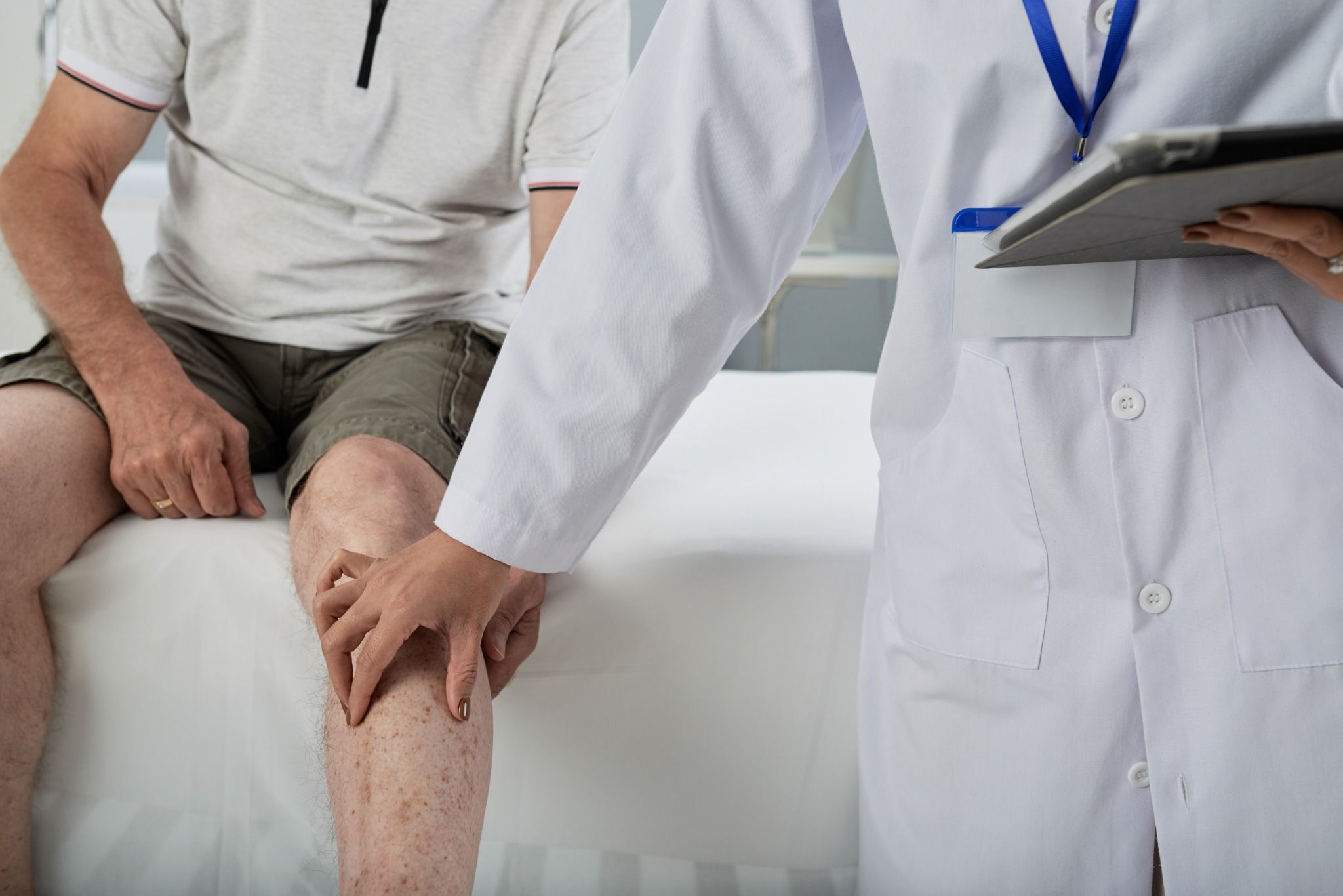 Doctor checking for tibial tuberosity experiencing knee pain.