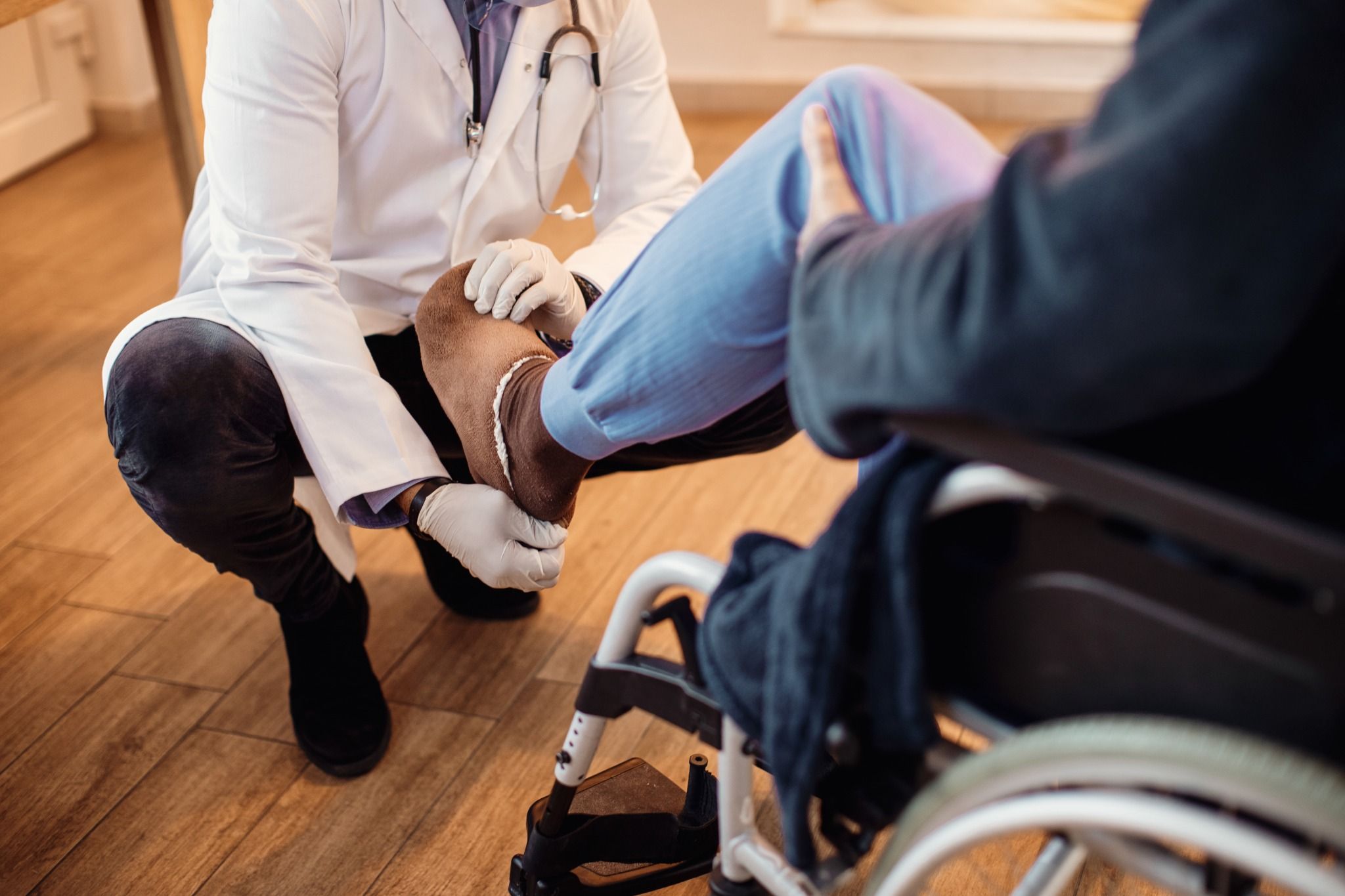 Doctor examining a patient’s knee during a medical checkup, assessing symptoms of osteoarthritis and joint pain.