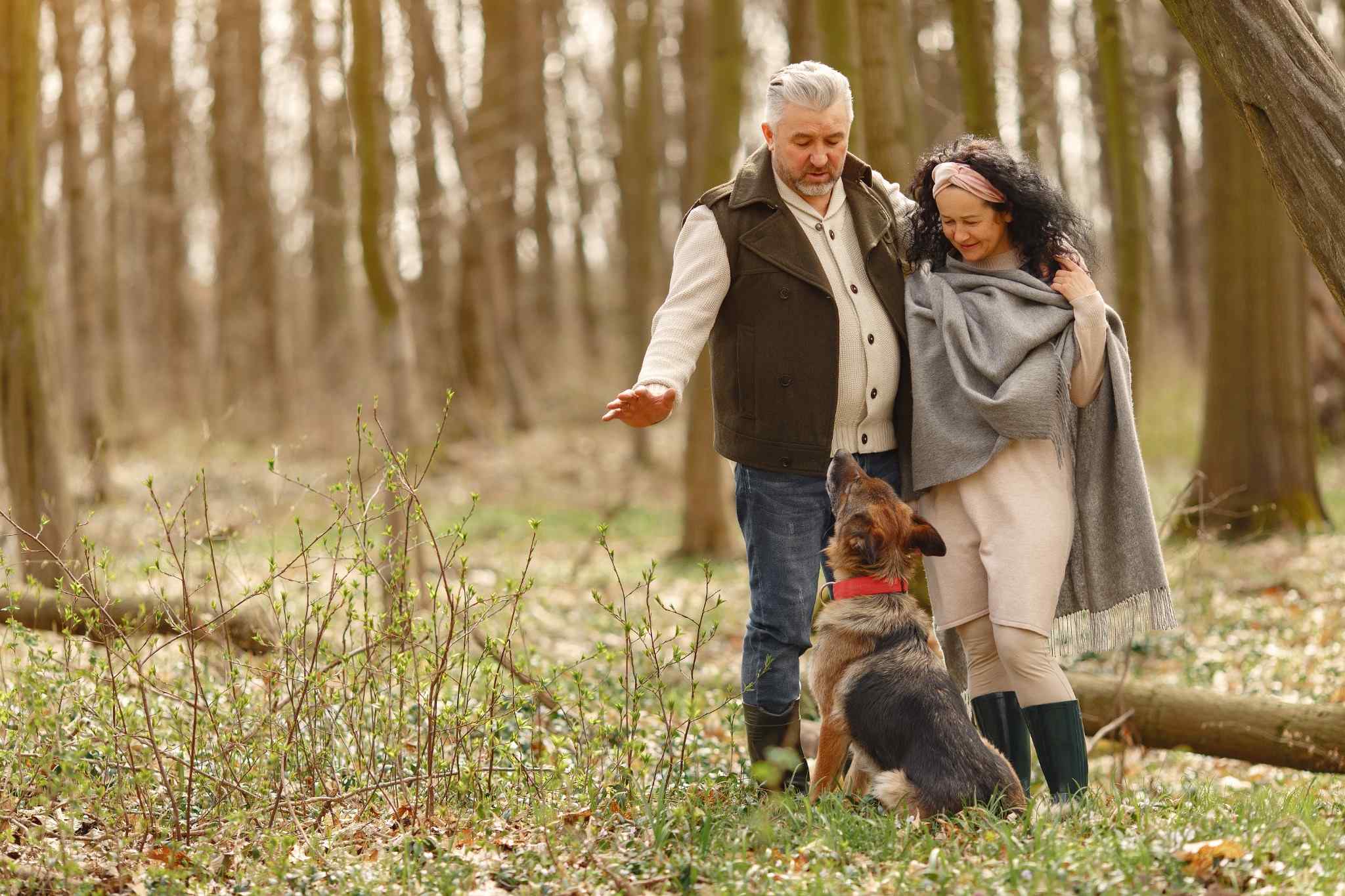 Older couple walking in the forest with their dog, symbolizing active living and knee health. Feeling good with knee pain relief.