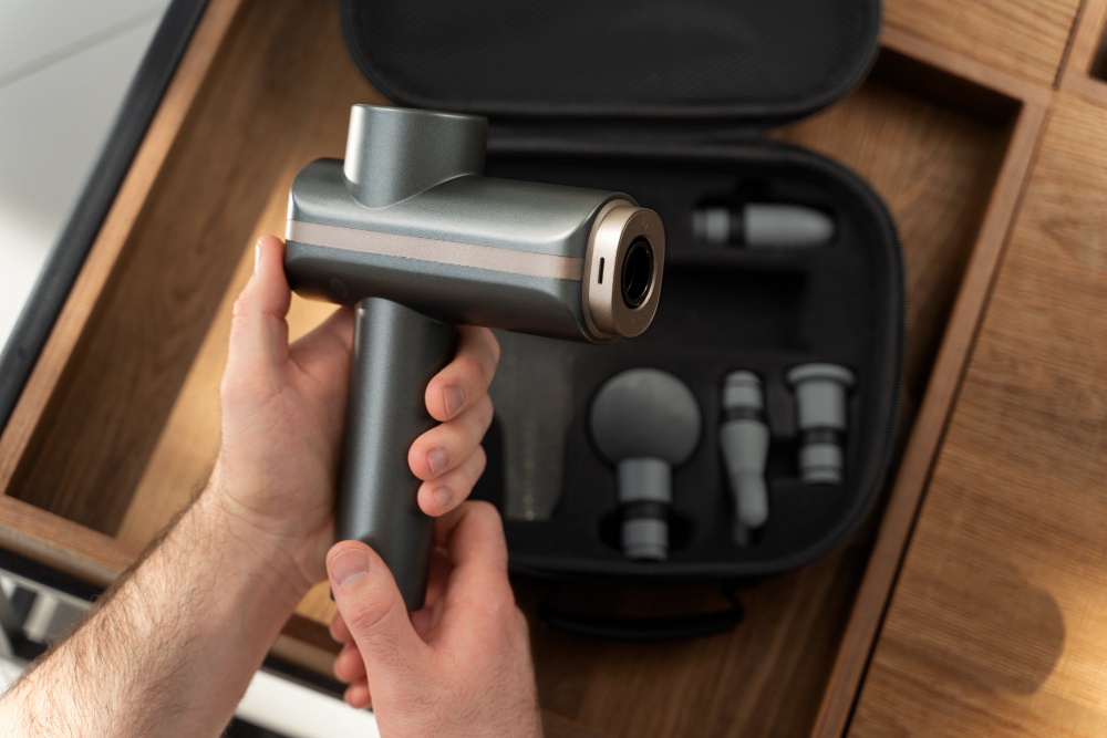 Person holding a handheld massage gun designed to relieve knee arthritis pain and stiffness.