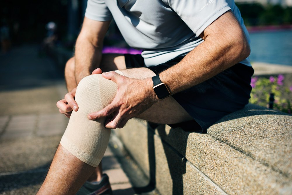 Man wearing a knee brace to ease pain and support mobility affected by a Baker’s cyst behind the knee.