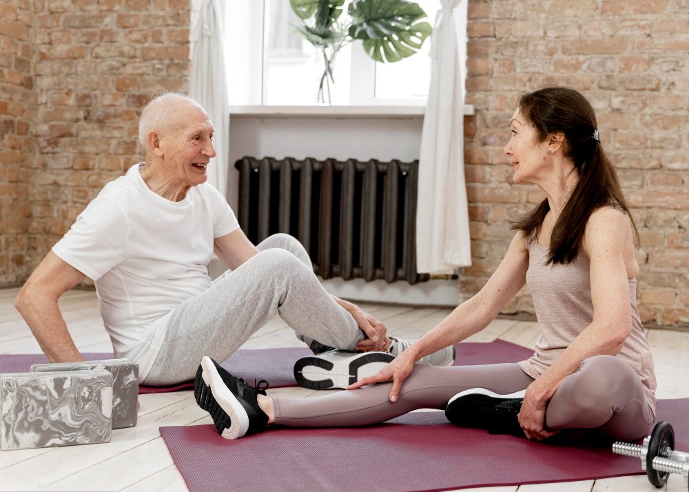 Alt Text: Senior couple performing knee flexion and extension stretches together on yoga mats to improve joint mobility and relieve knee pain.