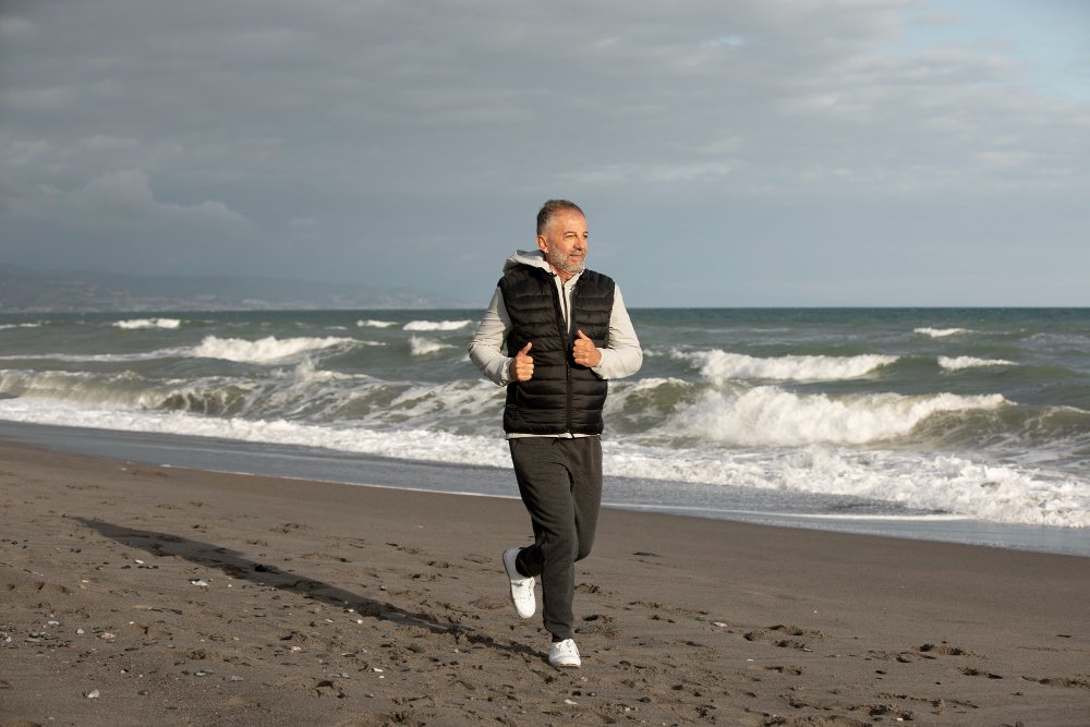 Man walking along the beach to strengthen leg alignment and improve knock knees posture.