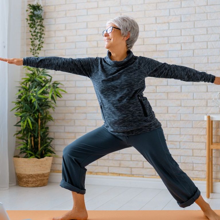 elderly woman doing yoga pose in living room